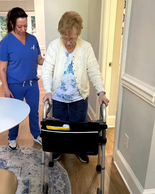 Summer Patel, Occupational Therapist, guiding an older woman using a walker at home.